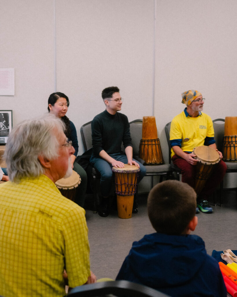 Photograph of people learning to play drums during a workshop at the 2025 Maple Sugar Festival.