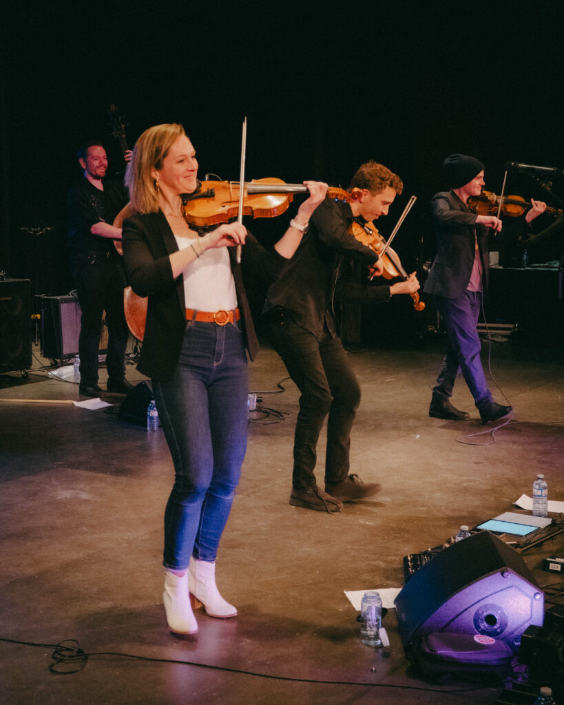 Photograph of musicians performing on stage at Maple Sugar Festival in Nanaimo, with a violin in the foreground.