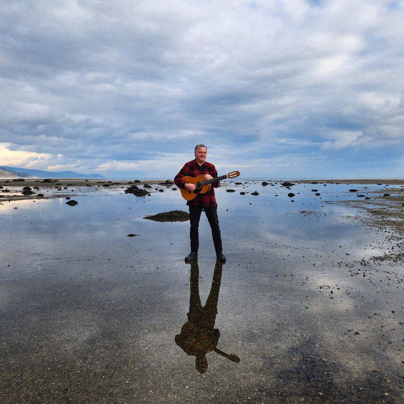 Photo of a Québec musician on the shore of a river.