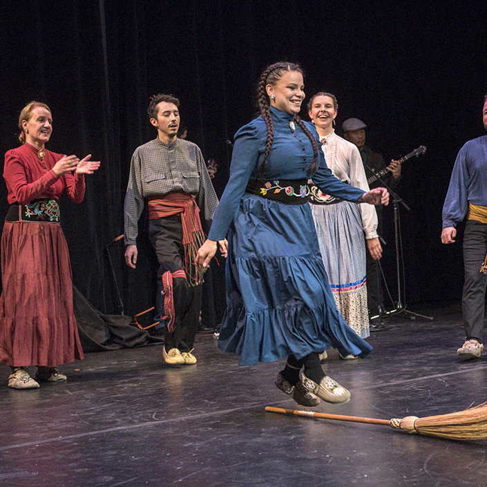 Photo of a group of metis dancers performing on stage.