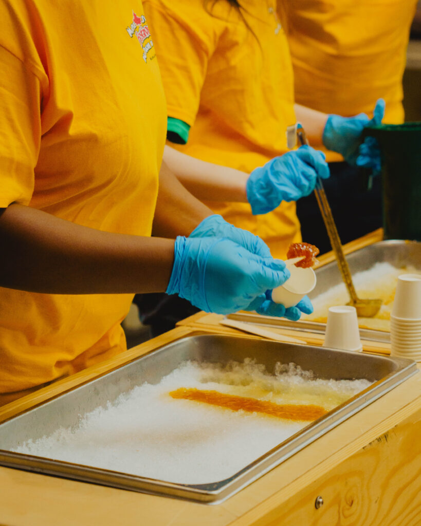 Photographie d’un banc de neige sur lequel on verse du sirop d’érable pour faire de la tire d’érable.