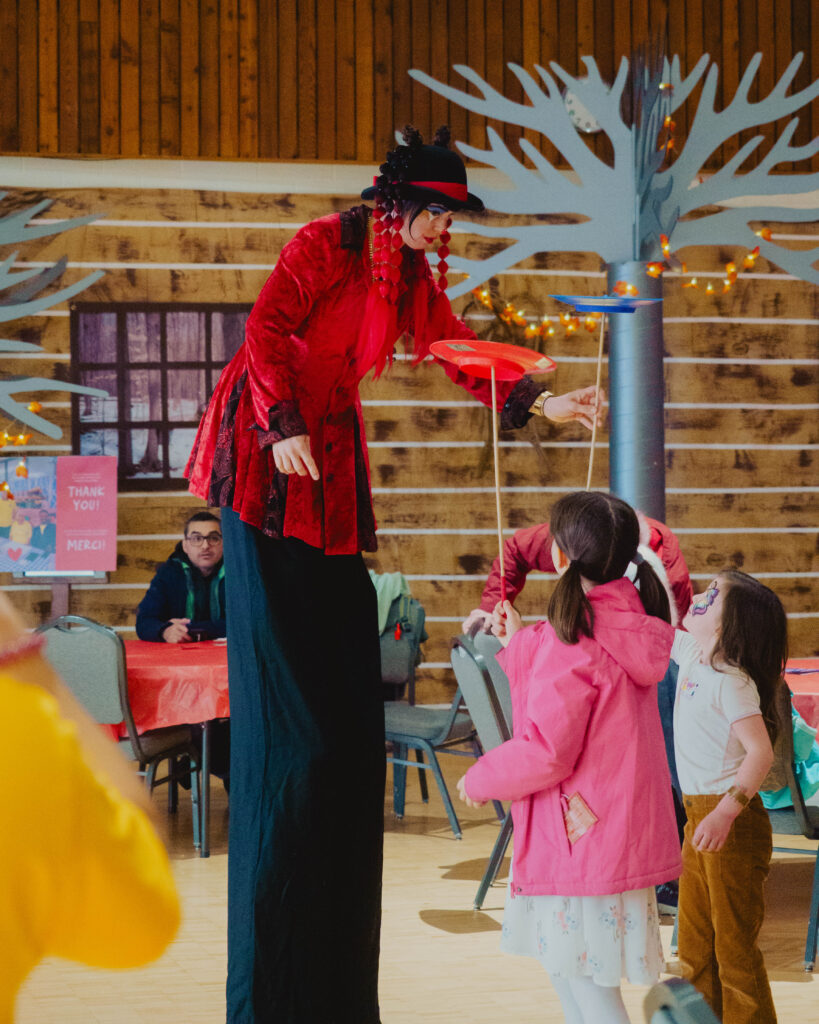 Une artiste de cirque fait essayer des jeux d'équilibre à des enfants.
